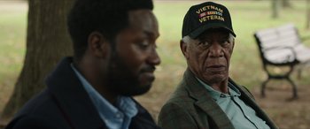 Movie still from “A Good Person” (2023), directed by Zach Braff – Two men sitting next to each other in front of trees; Close Up shot, Over the shoulder angle