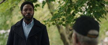 Movie still from “A Good Person” (2023), directed by Zach Braff – A man wearing a black coat standing in front of a tree; Close Up shot, Over the shoulder angle