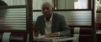 Movie still from “A Good Person” (2023), directed by Zach Braff – An older man sitting at a table in a restaurant; Medium shot, Over the shoulder angle