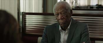 Movie still from “A Good Person” (2023), directed by Zach Braff – An older man sitting in a chair in front of a window; Close Up shot, Over the shoulder angle