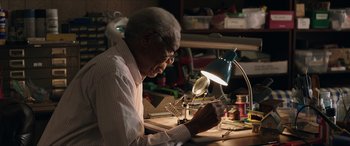 Movie still from “A Good Person” (2023), directed by Zach Braff – An older man working in a jewelry workshop; Medium shot, Low angle