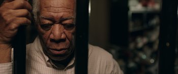 Movie still from “A Good Person” (2023), directed by Zach Braff – An older man is looking through the bars of a jail cell; Close Up shot, Low angle