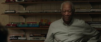 Movie still from “A Good Person” (2023), directed by Zach Braff – An older man sitting in front of a bookshelf; Close Up shot, Low angle
