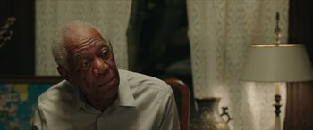 Movie still from “A Good Person” (2023), directed by Zach Braff – An older man sitting in a chair with his head resting on his arm; Close Up shot, Over the shoulder angle