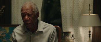 Movie still from “A Good Person” (2023), directed by Zach Braff – An older man sitting in a chair in front of a window; Close Up shot, Over the shoulder angle