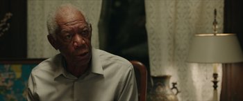 Movie still from “A Good Person” (2023), directed by Zach Braff – An older man sitting at a table in front of a window; Close Up shot, Over the shoulder angle