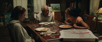Movie still from “A Good Person” (2023), directed by Zach Braff – An older man and a young girl sitting at a table with plates of food on it; Medium shot, High angle