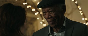 Movie still from “A Good Person” (2023), directed by Zach Braff – An older man wearing a hat and a jacket; Close Up shot, Over the shoulder angle
