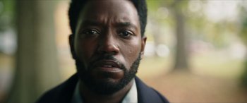 Movie still from “A Good Person” (2023), directed by Zach Braff – A person with a beard looking at the camera; Close Up shot, Over the shoulder angle