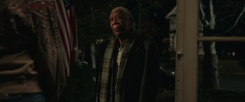 Movie still from “A Good Person” (2023), directed by Zach Braff – An older man wearing a scarf and a jacket; Medium shot, Low angle