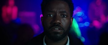 Movie still from “A Good Person” (2023), directed by Zach Braff – A man's face in front of neon lights; Close Up shot, Low angle