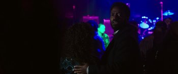 Movie still from “A Good Person” (2023), directed by Zach Braff – A man and a woman are standing in a dark room; Medium shot, Over the shoulder angle