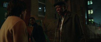 Movie still from “A Good Person” (2023), directed by Zach Braff – Two men standing next to each other in front of a brick building; Medium shot, Over the shoulder angle