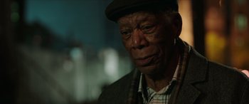 Movie still from “A Good Person” (2023), directed by Zach Braff – An older man wearing a hat and a plaid jacket; Close Up shot, Over the shoulder angle