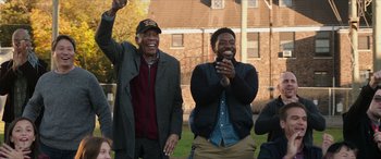 Movie still from “A Good Person” (2023), directed by Zach Braff – Two men are laughing and clapping while one of them holds a cell phone; Medium shot, Low angle