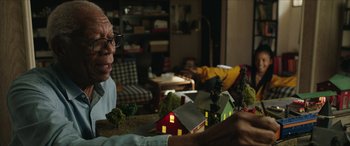 Movie still from “A Good Person” (2023), directed by Zach Braff – An older man sitting in front of a model village; Medium shot, Over the shoulder angle