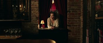 Movie still from “A Good Person” (2023), directed by Zach Braff – A woman sitting in front of a window with a lamp; Medium shot, Over the shoulder angle
