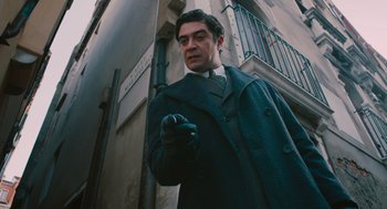 Movie still from “A Haunting in Venice” (2023), directed by Kenneth Branagh – A man in a suit and tie holding a cane; Medium shot, Low angle