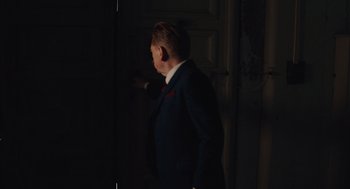 Movie still from “A Haunting in Venice” (2023), directed by Kenneth Branagh – A man in a suit and tie standing in front of an open door; Medium shot, Over the shoulder angle