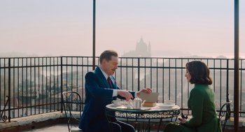 Movie still from “A Haunting in Venice” (2023), directed by Kenneth Branagh – A man sitting at a table with a plate in front of him; Medium shot, Over the shoulder angle