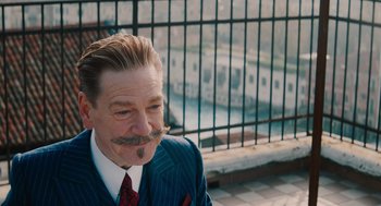 Movie still from “A Haunting in Venice” (2023), directed by Kenneth Branagh – A person wearing a suit and tie; Close Up shot, Over the shoulder angle