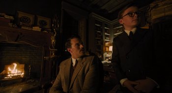 Movie still from “A Haunting in Venice” (2023), directed by Kenneth Branagh – A man in a suit sitting next to another man in a suit; Medium shot, Low angle