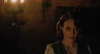 Movie still from “A Haunting in Venice” (2023), directed by Kenneth Branagh – A woman in a dark room looking at the camera; Close Up shot, Over the shoulder angle