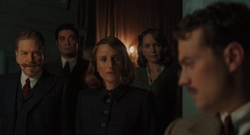Movie still from “A Haunting in Venice” (2023), directed by Kenneth Branagh – A group of people standing in front of a window; Medium shot, Over the shoulder angle