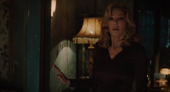 Movie still from “A Haunting in Venice” (2023), directed by Kenneth Branagh – A woman standing in front of a window in a dark room; Medium shot, Over the shoulder angle
