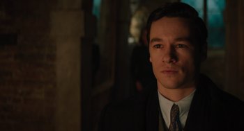 Movie still from “A Haunting in Venice” (2023), directed by Kenneth Branagh – A man wearing a suit and tie standing in front of a wall; Close Up shot, Over the shoulder angle
