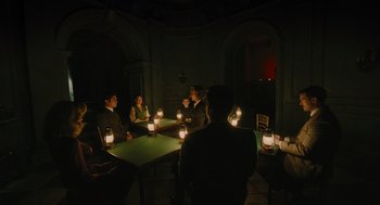 Movie still from “A Haunting in Venice” (2023), directed by Kenneth Branagh – A group of people sitting around a table with candles; Wide shot, High angle