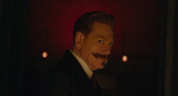 Movie still from “A Haunting in Venice” (2023), directed by Kenneth Branagh – A person wearing a suit and tie; Close Up shot, Low angle