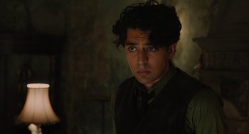 Movie still from “A Haunting in Venice” (2023), directed by Kenneth Branagh – A young man in a green shirt and a vest; Close Up shot, Over the shoulder angle