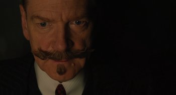 Movie still from “A Haunting in Venice” (2023), directed by Kenneth Branagh – A person wearing a suit and tie; Close Up shot, Low angle