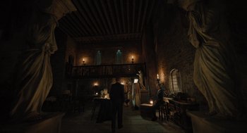Movie still from “A Haunting in Venice” (2023), directed by Kenneth Branagh – A group of people standing in a room with candles; Extreme Wide shot, Low angle