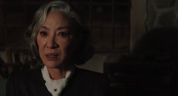 Movie still from “A Haunting in Venice” (2023), directed by Kenneth Branagh – An older woman in a black suit and white shirt; Close Up shot, Over the shoulder angle