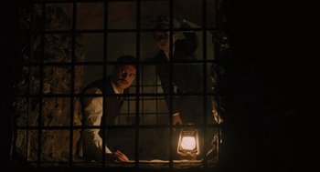 Movie still from “A Haunting in Venice” (2023), directed by Kenneth Branagh – Two men are standing in a jail cell; Medium shot, Low angle