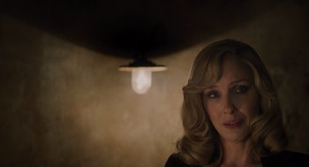 Movie still from “A Haunting in Venice” (2023), directed by Kenneth Branagh – A person wearing a black shirt near a light; Close Up shot, Over the shoulder angle