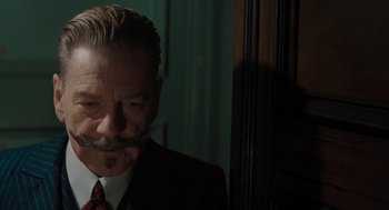 Movie still from “A Haunting in Venice” (2023), directed by Kenneth Branagh – An older man with a mustache wearing a suit and tie; Close Up shot, Over the shoulder angle