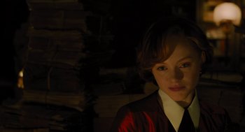 Movie still from “A Haunting in Venice” (2023), directed by Kenneth Branagh – A woman with short hair wearing a red and black jacket; Close Up shot, Over the shoulder angle