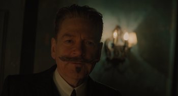 Movie still from “A Haunting in Venice” (2023), directed by Kenneth Branagh – A man wearing a suit and tie with a fake mustache; Close Up shot, Low angle