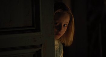 Movie still from “A Haunting in Venice” (2023), directed by Kenneth Branagh – A young girl is standing in a dark room; Close Up shot, Over the shoulder angle