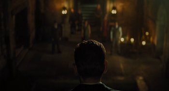 Movie still from “A Haunting in Venice” (2023), directed by Kenneth Branagh – A man is looking into a room with people in it; Wide shot, Over the shoulder angle