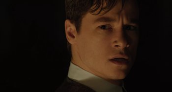 Movie still from “A Haunting in Venice” (2023), directed by Kenneth Branagh – A person wearing a suit and tie; Close Up shot, Low angle