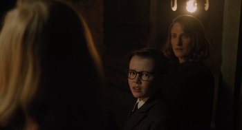 Movie still from “A Haunting in Venice” (2023), directed by Kenneth Branagh – A woman and a boy wearing glasses and a suit; Close Up shot, Over the shoulder angle