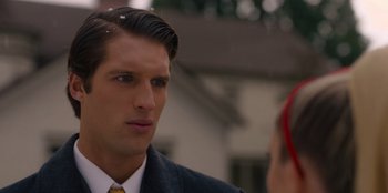 Movie still from “A Hollywood Christmas” (2022), directed by Alex Ranarivelo – A man wearing a suit and tie talking to a woman wearing a yellow tie; Close Up shot, Over the shoulder angle