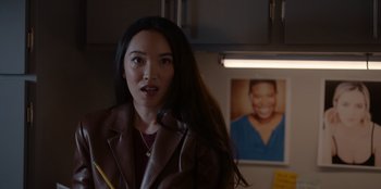 Movie still from “A Hollywood Christmas” (2022), directed by Alex Ranarivelo – A woman holding a microphone in a room with pictures on the wall; Close Up shot, Over the shoulder angle