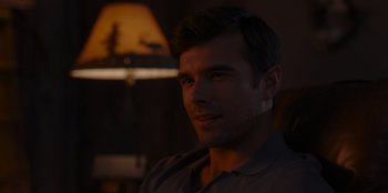 Movie still from “A Hollywood Christmas” (2022), directed by Alex Ranarivelo – A man sitting in front of a lamp in a room; Close Up shot, Over the shoulder angle