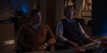 Movie still from “A Hollywood Christmas” (2022), directed by Alex Ranarivelo – Two men are sitting in a dark room; Medium shot, Over the shoulder angle