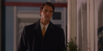 Movie still from “A Hollywood Christmas” (2022), directed by Alex Ranarivelo – A man wearing a suit and tie standing next to a window; Close Up shot, Over the shoulder angle